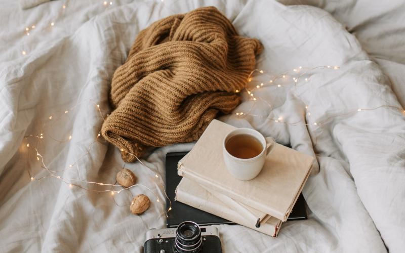 a warm sweater and tea on a bed