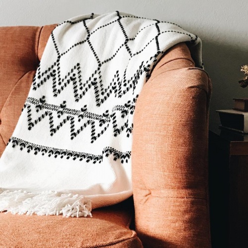 a couch with a blanket on it in a well-lit room